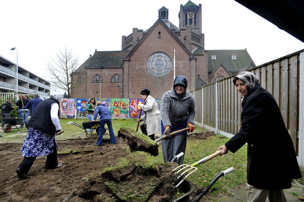 2011 Tilburg Islamitische vrouwen werken aan de moestuin van buurthuis De Spil, terwijl de katholieke kerk over hun tuintje waakt.